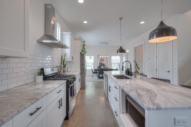 kitchen featuring pendant lighting, sink, wall chimney range hood, and appliances with stainless steel finishes