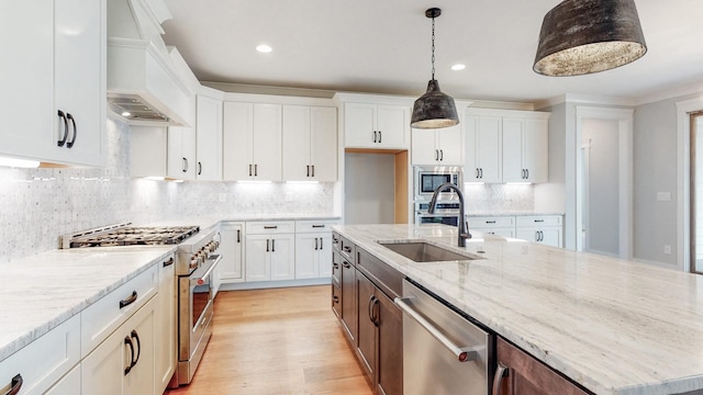 kitchen with white cabinets, stainless steel appliances, a center island with sink, and sink