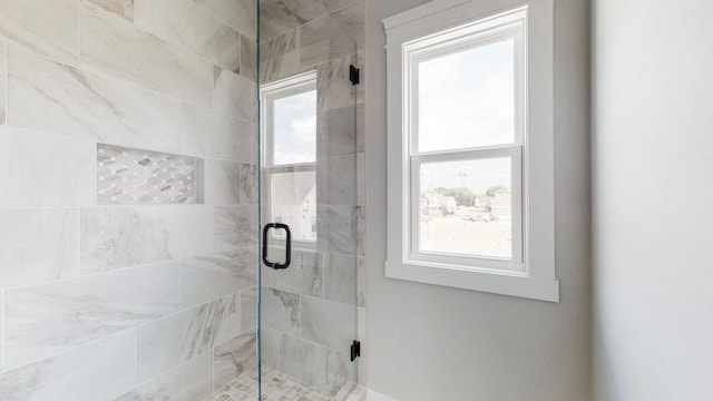 bathroom with a shower with shower door and a wealth of natural light