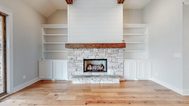 unfurnished living room featuring light wood-type flooring, vaulted ceiling, and a stone fireplace