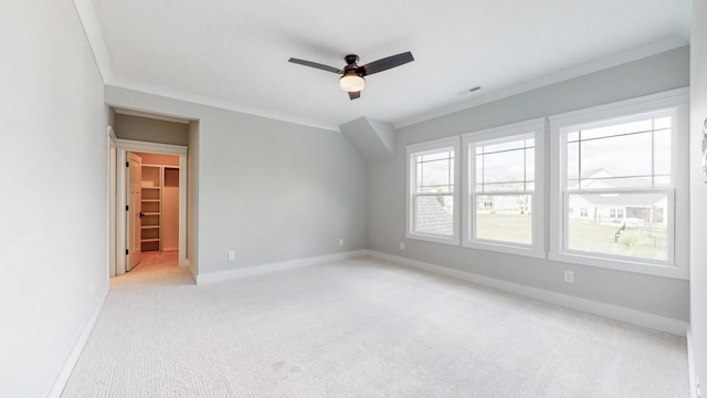 unfurnished bedroom with a spacious closet, a closet, ornamental molding, ceiling fan, and light colored carpet