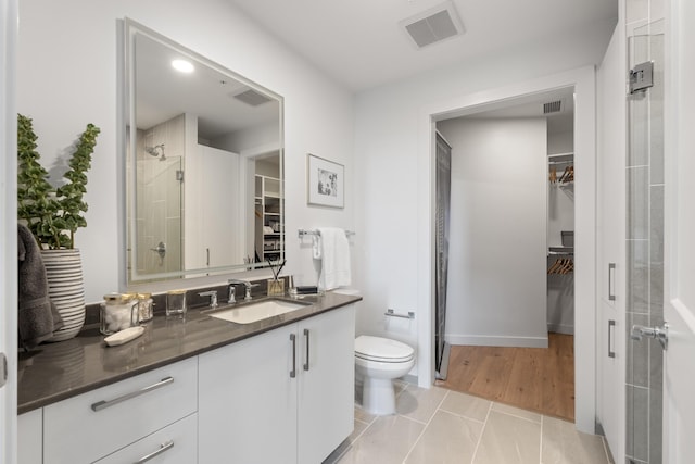 bathroom featuring walk in shower, toilet, tile patterned floors, and vanity