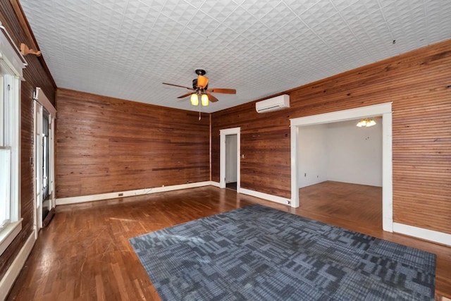 spare room featuring ceiling fan, dark hardwood / wood-style floors, wooden walls, and a wall mounted air conditioner