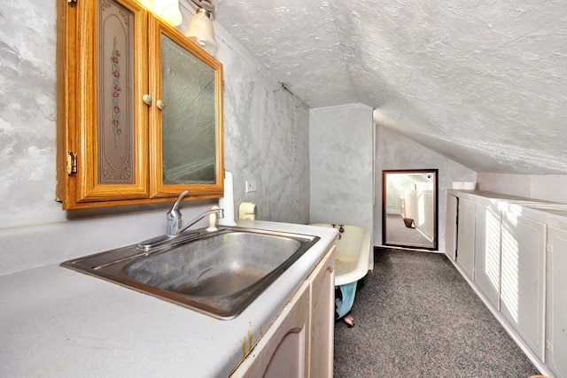 bathroom with a textured ceiling, vanity, and lofted ceiling