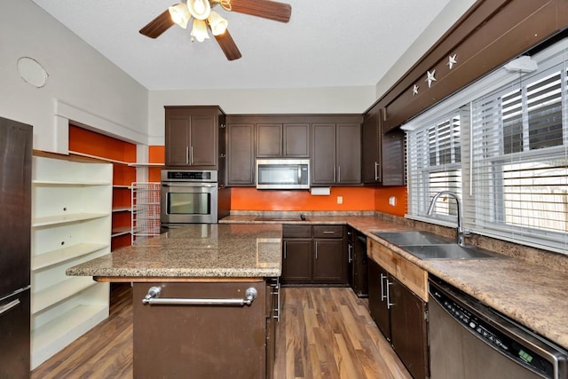 kitchen featuring dark brown cabinetry, stainless steel appliances, sink, a kitchen breakfast bar, and light hardwood / wood-style flooring