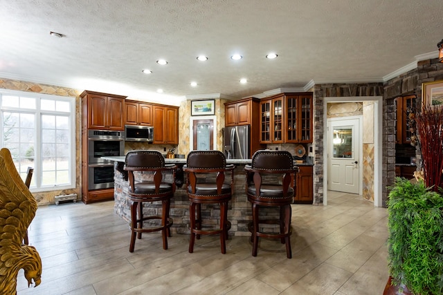 kitchen with an island with sink, appliances with stainless steel finishes, a breakfast bar area, and a textured ceiling