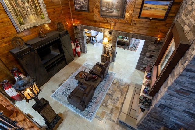 living room featuring high vaulted ceiling, a fireplace, and wooden walls