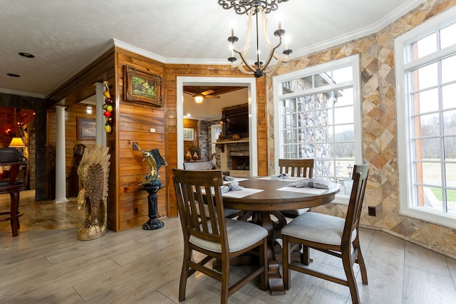 dining room with decorative columns, ornamental molding, a notable chandelier, and a fireplace