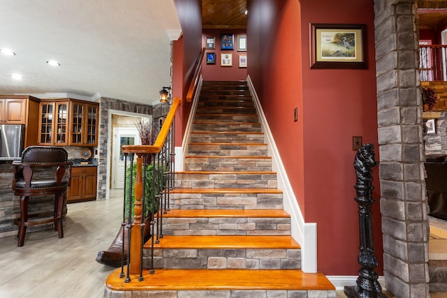 stairway with crown molding and hardwood / wood-style floors