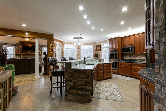 kitchen featuring pendant lighting, sink, a breakfast bar area, appliances with stainless steel finishes, and an island with sink