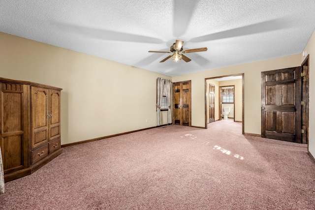 unfurnished bedroom featuring ceiling fan, a textured ceiling, light carpet, and ensuite bath