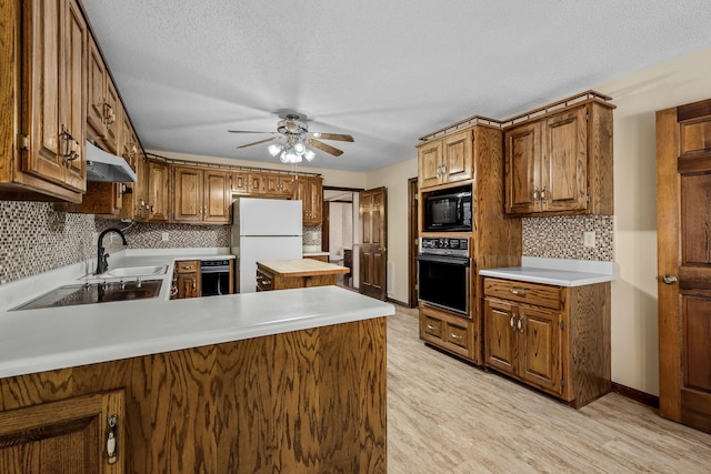 kitchen with black appliances, light hardwood / wood-style floors, sink, kitchen peninsula, and ceiling fan