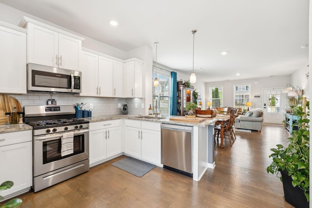 kitchen featuring appliances with stainless steel finishes, decorative light fixtures, white cabinetry, light stone counters, and decorative backsplash