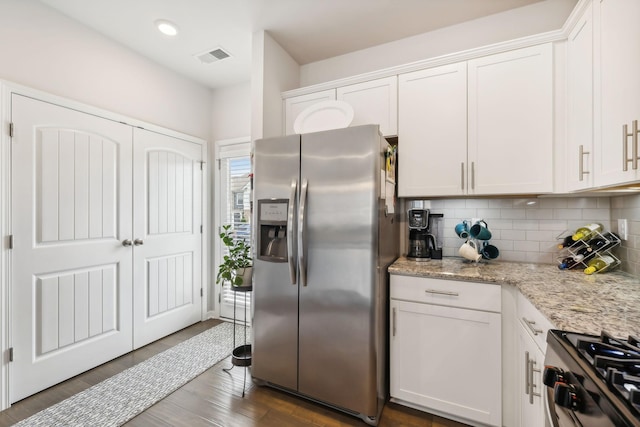 kitchen featuring appliances with stainless steel finishes, white cabinetry, dark hardwood / wood-style flooring, backsplash, and light stone counters