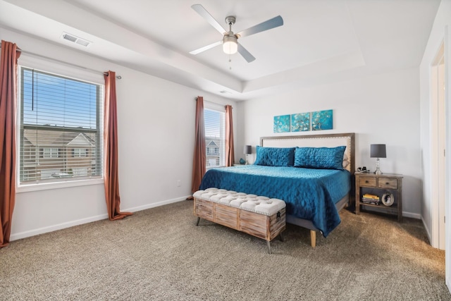 carpeted bedroom featuring ceiling fan and a tray ceiling