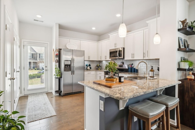 kitchen featuring white cabinets, decorative light fixtures, stainless steel appliances, sink, and kitchen peninsula