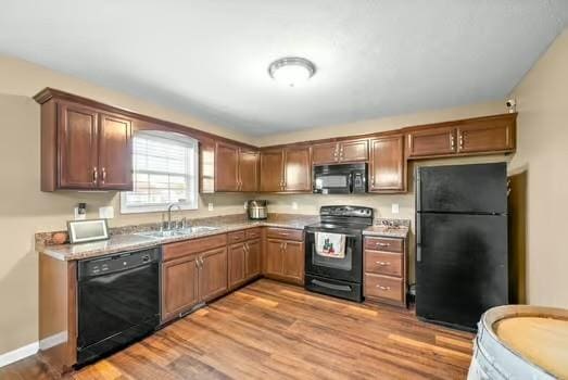 kitchen featuring sink, black appliances, and light hardwood / wood-style flooring