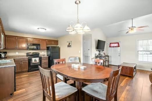 dining area with light wood-type flooring, ceiling fan with notable chandelier, lofted ceiling, and sink