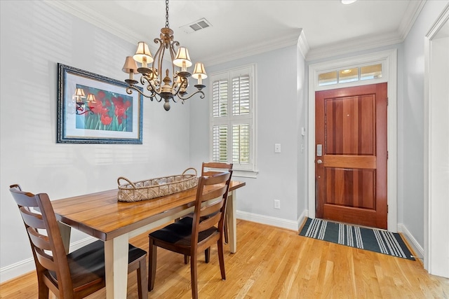 dining space with an inviting chandelier, ornamental molding, and light wood-type flooring