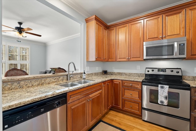 kitchen with ornamental molding, appliances with stainless steel finishes, sink, and light wood-type flooring