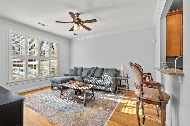 living room featuring crown molding, ceiling fan, and light hardwood / wood-style flooring