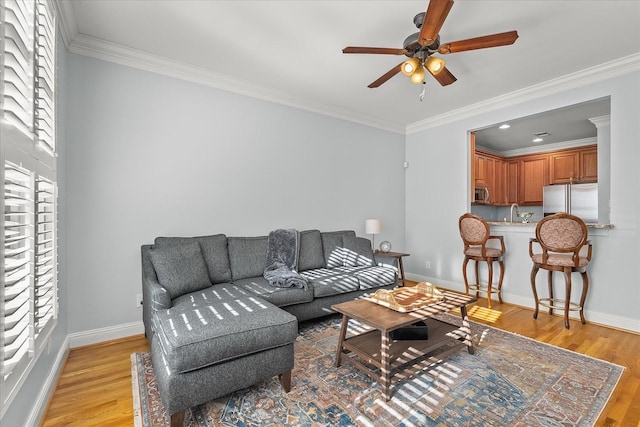 living room featuring crown molding, ceiling fan, plenty of natural light, and light wood-type flooring