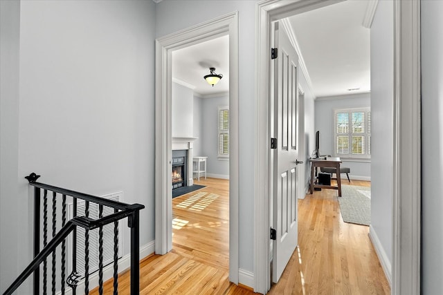 corridor with ornamental molding and light wood-type flooring