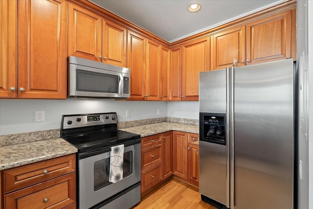 kitchen featuring appliances with stainless steel finishes, light stone counters, and light hardwood / wood-style floors