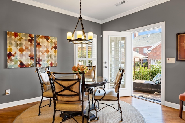 dining area with a notable chandelier, crown molding, and wood-type flooring