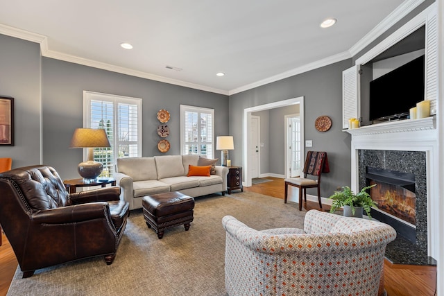 living room with ornamental molding, a high end fireplace, and hardwood / wood-style floors