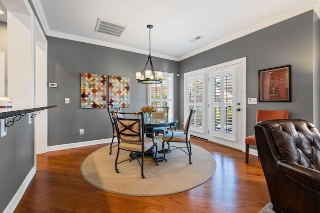 dining space with dark hardwood / wood-style flooring, crown molding, and a chandelier