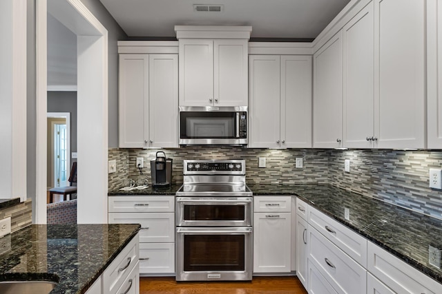 kitchen with stainless steel appliances, white cabinets, and decorative backsplash