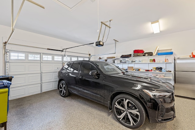 garage with a garage door opener and stainless steel refrigerator