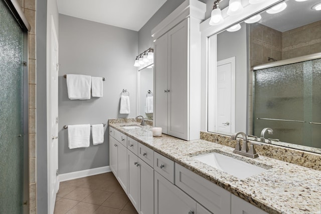 bathroom with tile patterned floors, a shower with door, and vanity