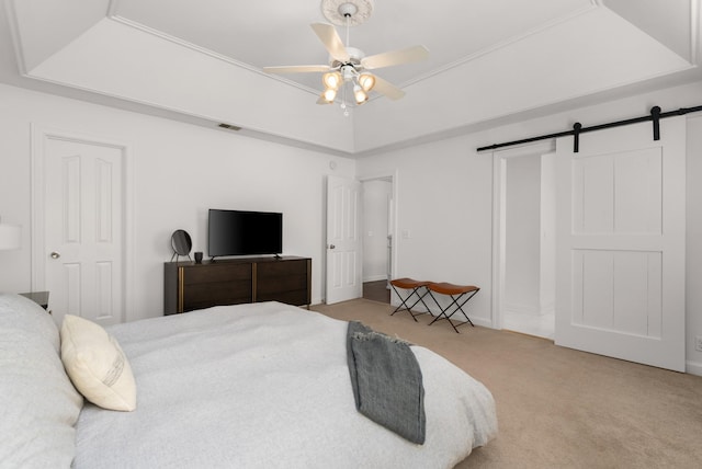 carpeted bedroom with a barn door, ceiling fan, and a raised ceiling