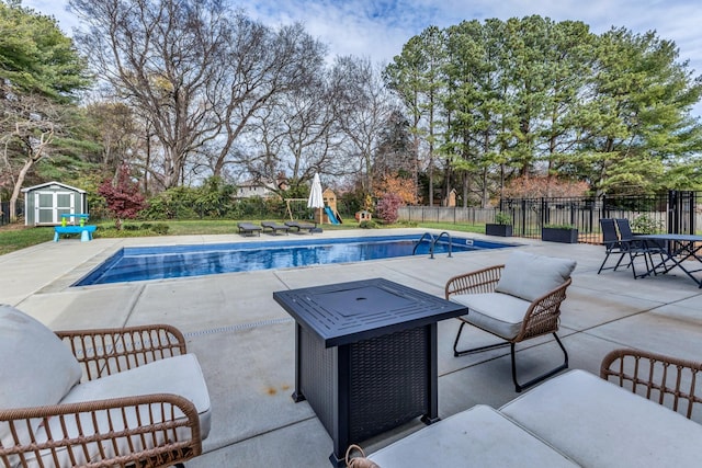 view of swimming pool featuring a patio area, an outdoor hangout area, a playground, and a storage unit