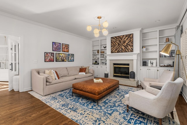 living room featuring dark hardwood / wood-style flooring, built in features, a chandelier, a brick fireplace, and crown molding