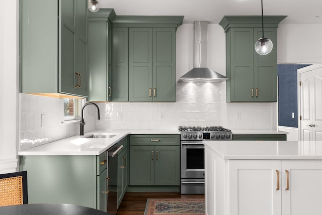 kitchen with green cabinets, hanging light fixtures, wall chimney exhaust hood, sink, and stainless steel appliances