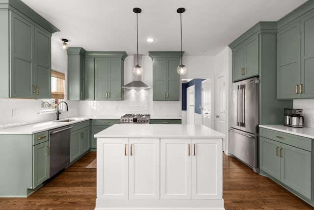 kitchen with appliances with stainless steel finishes, wall chimney range hood, a kitchen island, decorative light fixtures, and dark hardwood / wood-style floors