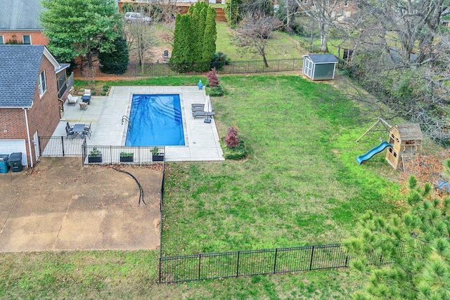 view of swimming pool featuring a playground, a patio area, a storage shed, and a lawn