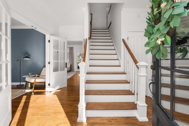 staircase with hardwood / wood-style flooring, french doors, and ornamental molding