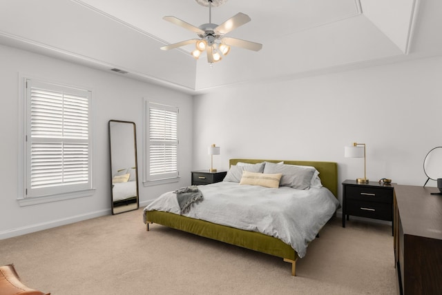 bedroom with ceiling fan, light carpet, and a tray ceiling