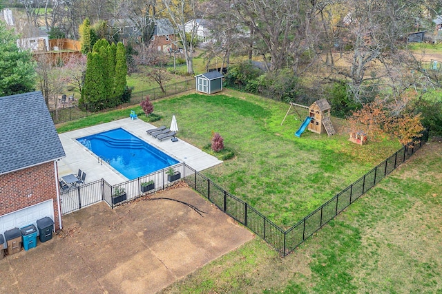 view of swimming pool featuring a patio area, a yard, a storage shed, and a playground