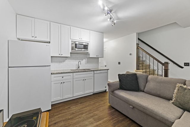 kitchen with white cabinetry, white appliances, light stone countertops, and sink