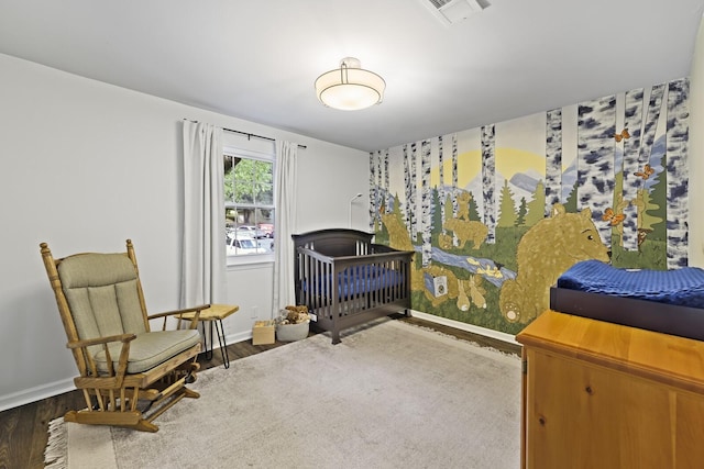 bedroom with hardwood / wood-style flooring and a nursery area