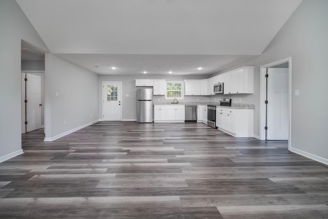 kitchen with white cabinets, vaulted ceiling, appliances with stainless steel finishes, and sink