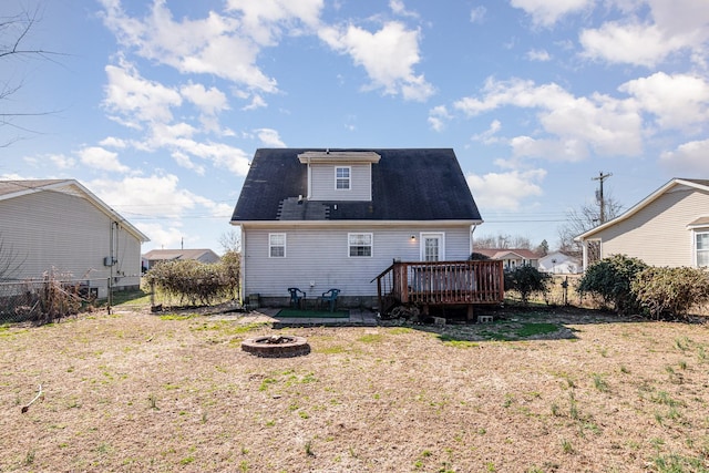 back of property featuring a deck, a lawn, and an outdoor fire pit