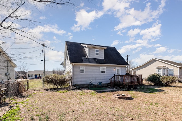 rear view of house featuring a wooden deck, a yard, and a fire pit