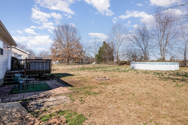 view of yard with a swimming pool side deck and a fire pit