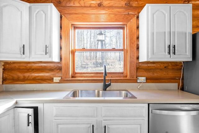 kitchen with sink, stainless steel dishwasher, white cabinets, and rustic walls